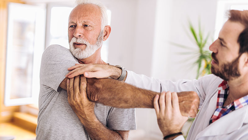 Elderly man getting shoulder adjustment by chiropractor